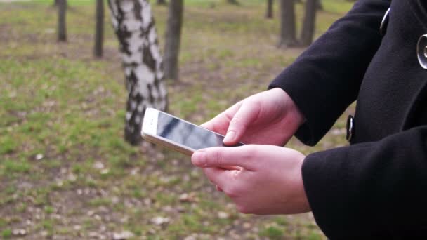 Jeune femme utilisant un smartphone dans le parc de la ville 