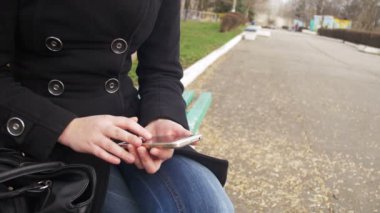 Şehir parkta bir bankta bir cep telefonu kullanan genç kız