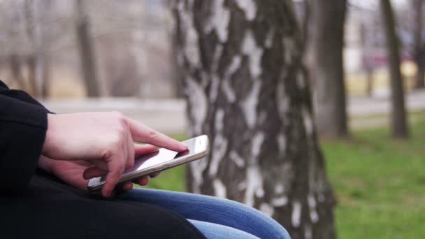 Jeune fille utilisant un téléphone portable sur un banc dans le parc de la ville 