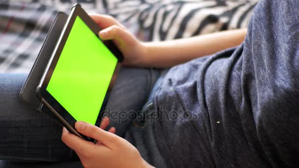 Молодая женщина лежит на кровати и с помощью планшета с зеленым экраном дома . — стоковое видео