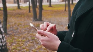Genç şehir parkında bir akıllı telefon kullanan kadın