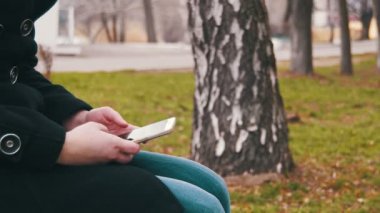 Şehir parkta bir bankta bir cep telefonu kullanan genç kız