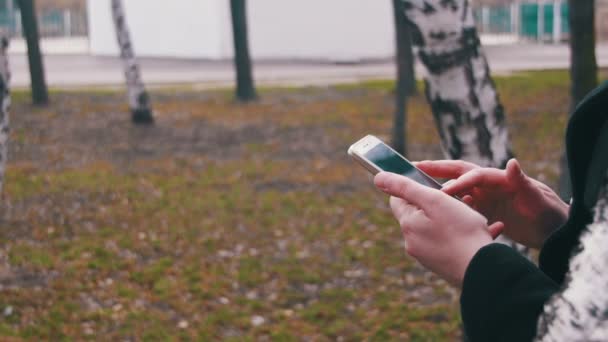 Menina usando um telefone celular no parque da cidade — Vídeo de Stock