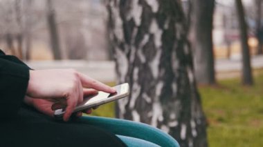 Genç şehir parkta bir bankta bir akıllı telefon kullanan kadın