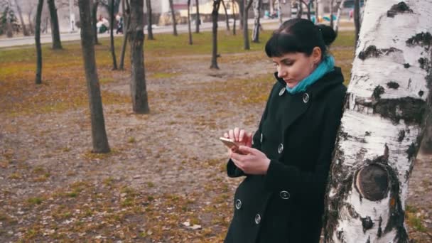 Genç şehir parkında bir akıllı telefon kullanan kadın — Stok video