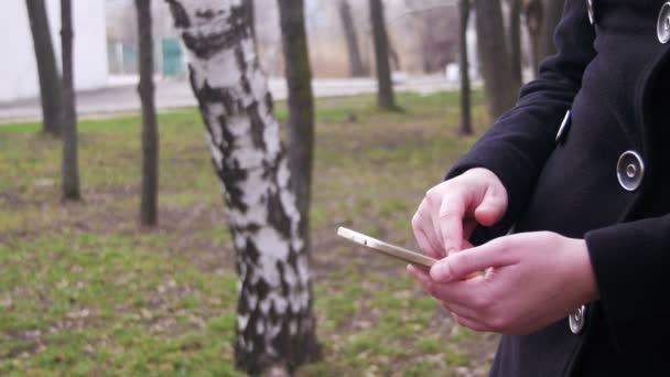 Jeune femme utilisant un smartphone dans le parc de la ville — Video