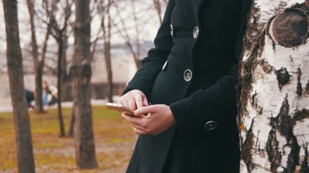 Jeune fille utilisant un téléphone portable dans le parc de la ville — Video