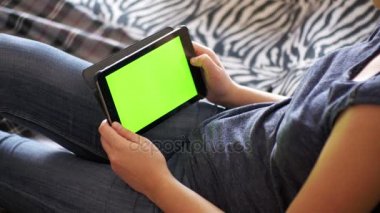 Kız Lying yatak ve Tablet Yeşil perde ile evde kullanma.