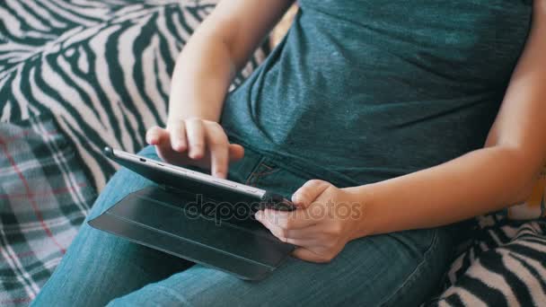 Молодая женщина лежит на кровати и с помощью планшета дома . — стоковое видео