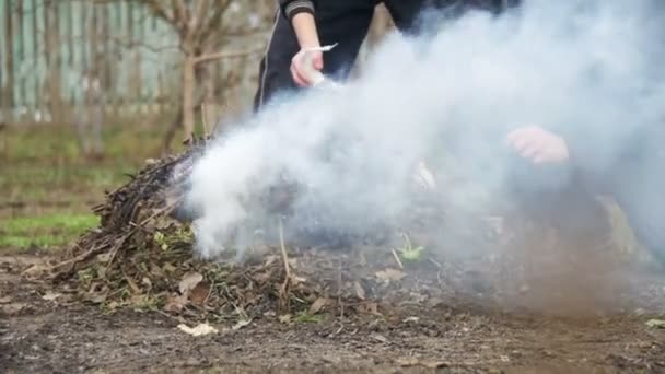 Brûler les débris, les feuilles, les petits arbres et les mauvaises herbes dans le jardin sur sa propre parcelle. Mouvement lent — Video