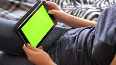 Kız Lying yatak ve Tablet Yeşil perde ile evde kullanma.