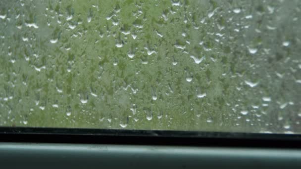 Gotas de lluvia en la ventana y lluvia detrás de la ventana de plástico — Vídeos de Stock