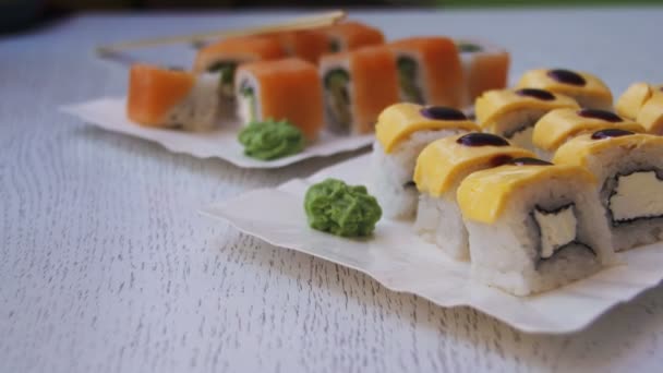 Rolos de sushi frescos em um restaurante em uma mesa de madeira branca elegante — Vídeo de Stock