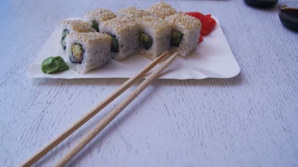 寿司のプレートは日本のレストランで白いスタイリッシュな木製のテーブル ロールします。ドリー ショット — ストック動画