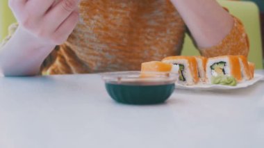 Kadın bir plaka suşi Japon restoranında yemek yemek çubukları ile. Dolly atış