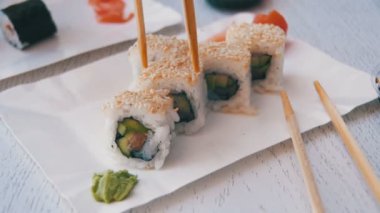 Bir tabak ve Dips içine soya sosu bir Japon restoranında suşi Roll alarak yemek çubukları. Ağır çekim