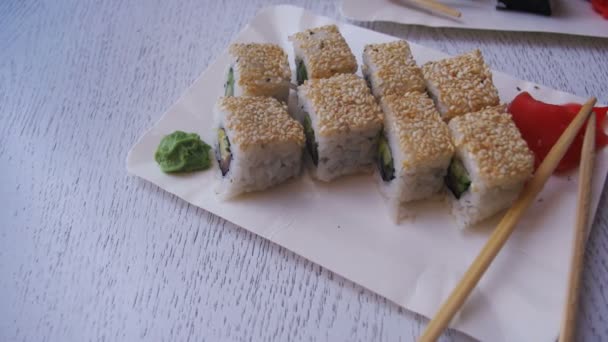 Suşi plakaları beyaz şık ahşap bir masa üzerinde bir Japon restoranında alır. Dolly atış — Stok video
