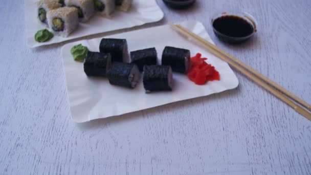 Platos de rollos de sushi en un restaurante japonés sobre una mesa de madera blanca con estilo. Dolly Shot — Vídeos de Stock