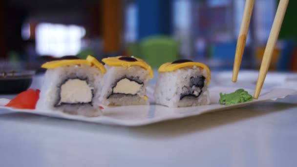 Par med ätpinnar tar Wasabi från en platta på en japansk restaurang — Stockvideo