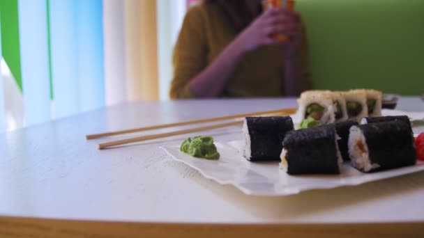 Platos de rollos de sushi en un restaurante japonés sobre una mesa de madera blanca con estilo. Dolly Shot — Vídeo de stock