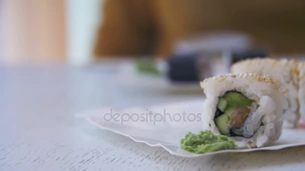 Assiette avec des rouleaux de sushi frais dans un restaurant japonais sur une table en bois blanc élégant. Dolly Shot — Video