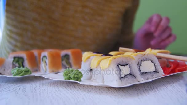 Frau mit Essstäbchen holt in japanischem Restaurant Sushi vom Teller — Stockvideo