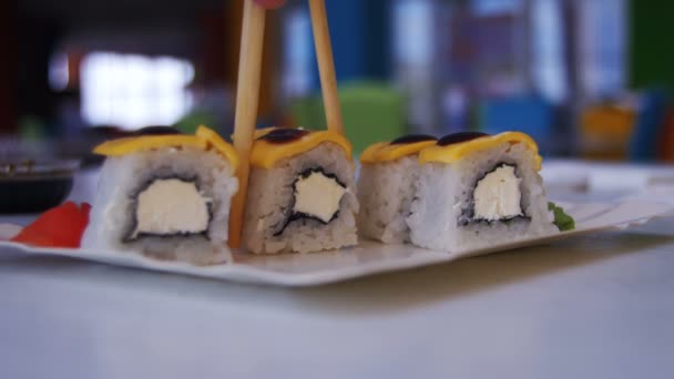 Vrouw met stokjes neemt Sushi van een plaat in een Japans Restaurant — Stockvideo