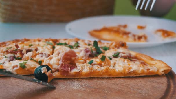 Mädchenhände schneiden eine Scheibe Pizza und legen sie auf einen Teller im Café. Kugelstoßer — Stockvideo