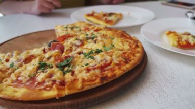 Kız beyaz tabakta bir beyaz tahta masada bir restoranda Pizza yiyor. Dolly atış