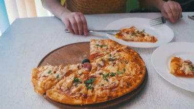 Kız beyaz tabakta bir beyaz tahta masada bir restoranda Pizza yiyor. Dolly atış