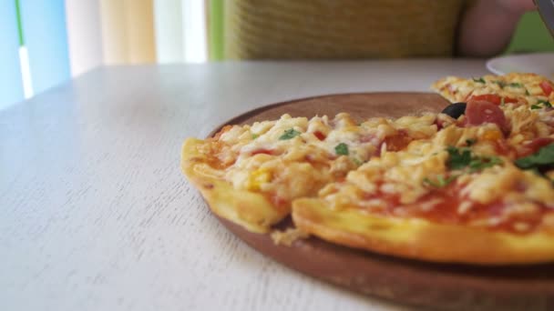 Chica es rebanada de Pizza en un plato blanco en un restaurante en una mesa de madera blanca. Dolly Shot — Vídeos de Stock