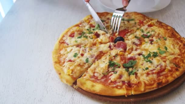 Женские руки режут кусочек пиццы и кладут его на тарелку в кафе — стоковое видео
