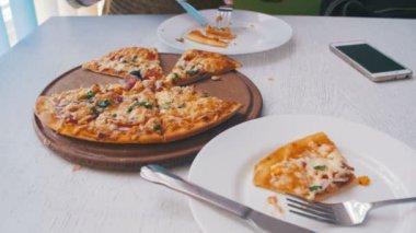Bir beyaz şık ahşap masa üstünde hareket eden telefon ile bir Cafe Pizza yeme kadındır