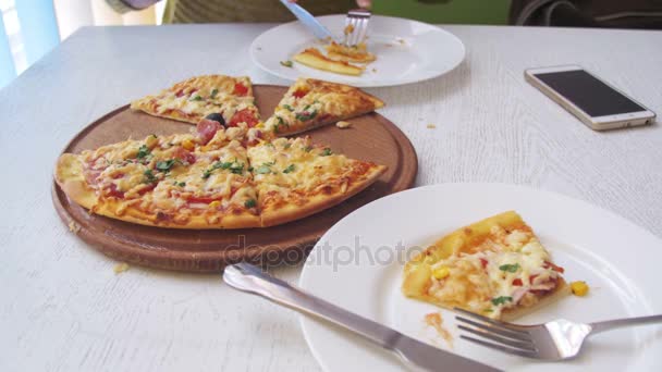 Dziewczyna jest jedzenie Pizza w Cafe z telefonu komórkowego na stół drewniany stylowy biały — Wideo stockowe