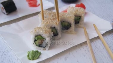 Bir tabak ve Dips içine soya sosu bir Japon restoranında suşi Roll alarak yemek çubukları. Ağır çekim