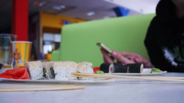 Homem usa um telefone celular em um restaurante japonês Sushi — Vídeo de Stock