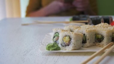 Suşi plakaları beyaz şık ahşap bir masa üzerinde bir Japon restoranında alır. Dolly atış