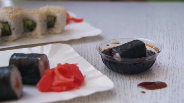 Chopsticks Levando Sushi Roll com Nori em molho de soja em um restaurante japonês. Movimento lento — Vídeo de Stock