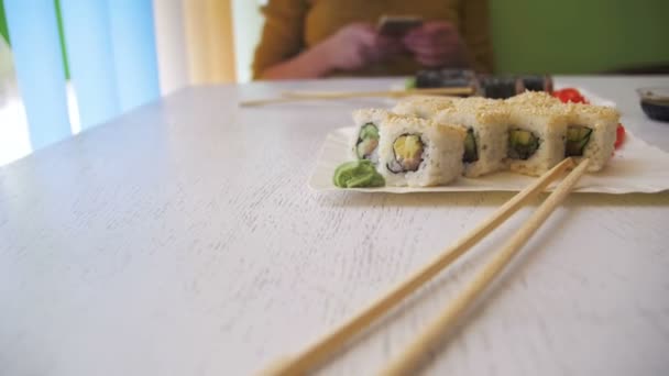 Suşi plakaları beyaz şık ahşap bir masa üzerinde bir Japon restoranında alır. Dolly atış — Stok video