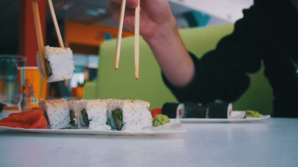 Par med ätpinnar tar Sushi från en platta på en japansk restaurang — Stockvideo