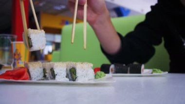 Bir plaka bir Japon restoranında yemek çubuğu alır suşi ile Çift