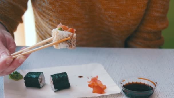 Frau isst Sushi-Rolle von einem Teller in einem japanischen Restaurant. Zeitlupe