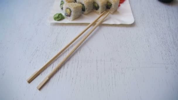 新鮮な寿司とプレートは日本のレストランでスタイリッシュな白い木製のテーブル ロールします。ドリー ショット — ストック動画