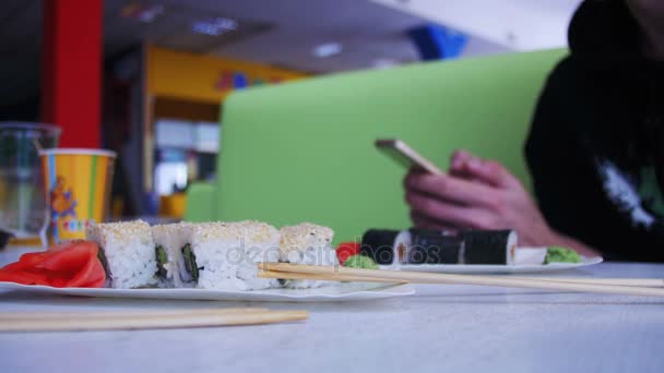 Homem usa um telefone celular em um restaurante japonês Sushi — Vídeo de Stock