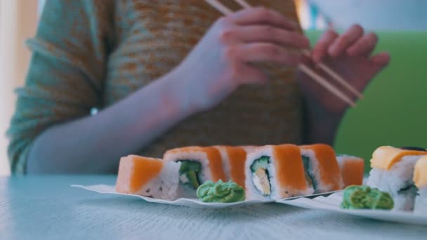 Femme avec des baguettes prend des sushis d'une assiette dans un restaurant japonais. Dolly Shot — Video