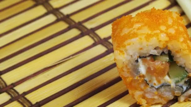 Un rotolo di sushi su un tappetino di bambù ruota — Video Stock