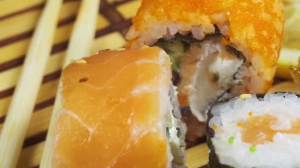 Rollos de sushi en una estera de bambú gira — Vídeo de stock