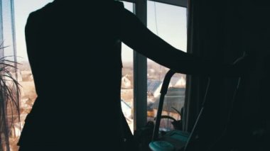 Siluet kızı evde eğitmen olarak cama çapraz kardiyo eğitmen üzerinde egzersiz.