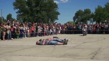 Yalan insanlar aracılığıyla trambolin üzerinde motosiklet atlama. Moto hüner. Dublör Moto Show. Ağır çekim