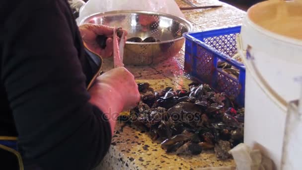Продавец рыбы очищает мидии на рыбном рынке — стоковое видео